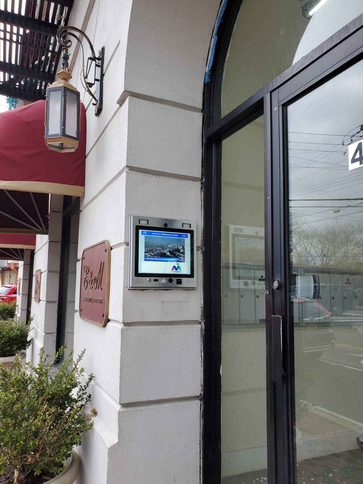 mvi keycom mounted on white stone wall by apartment building entrance