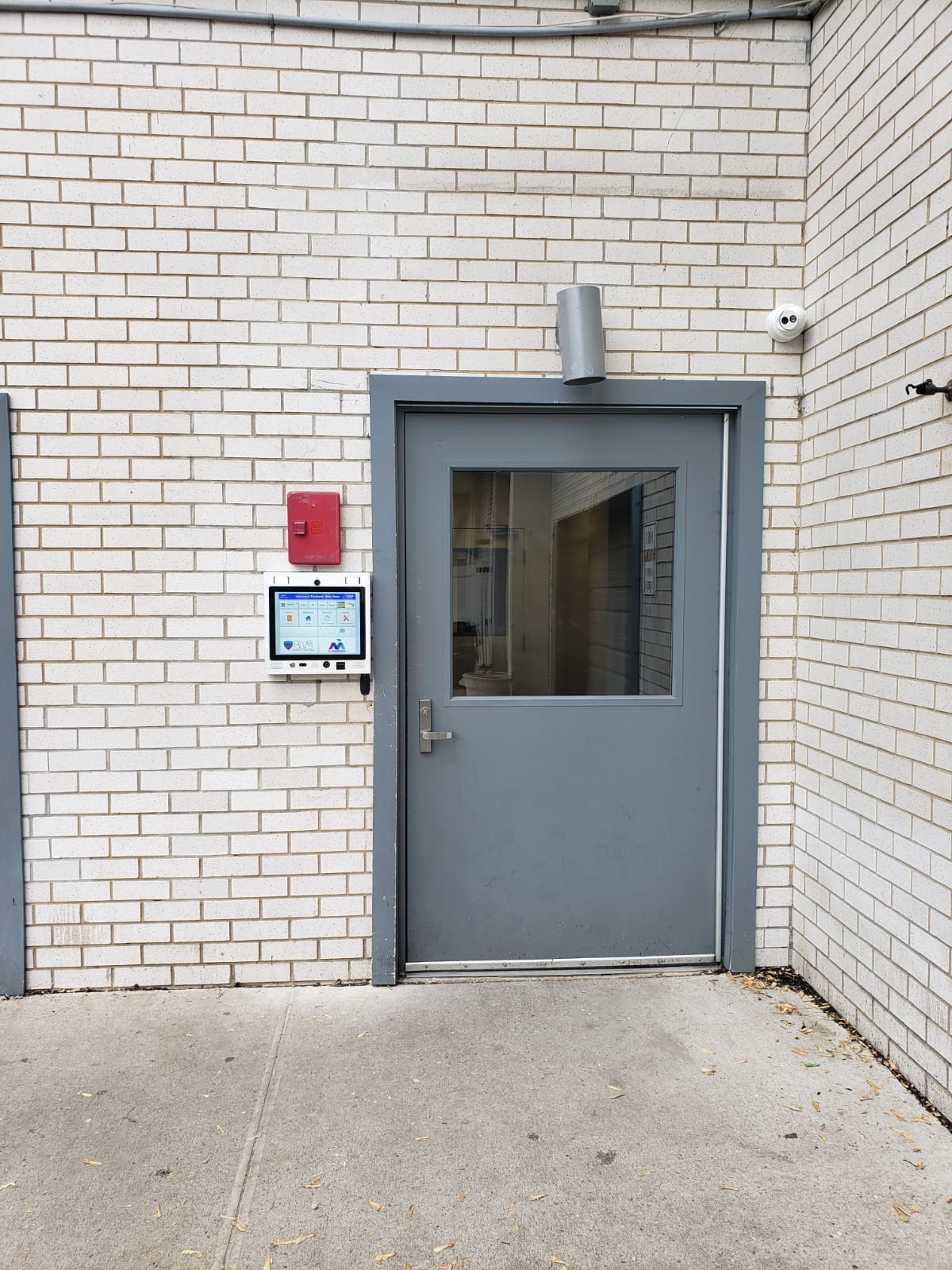 mvi keycom mounted on white brick wall by building entrance