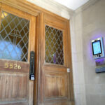 mvi keycom mounted on white stone wall next to wood door building entrance