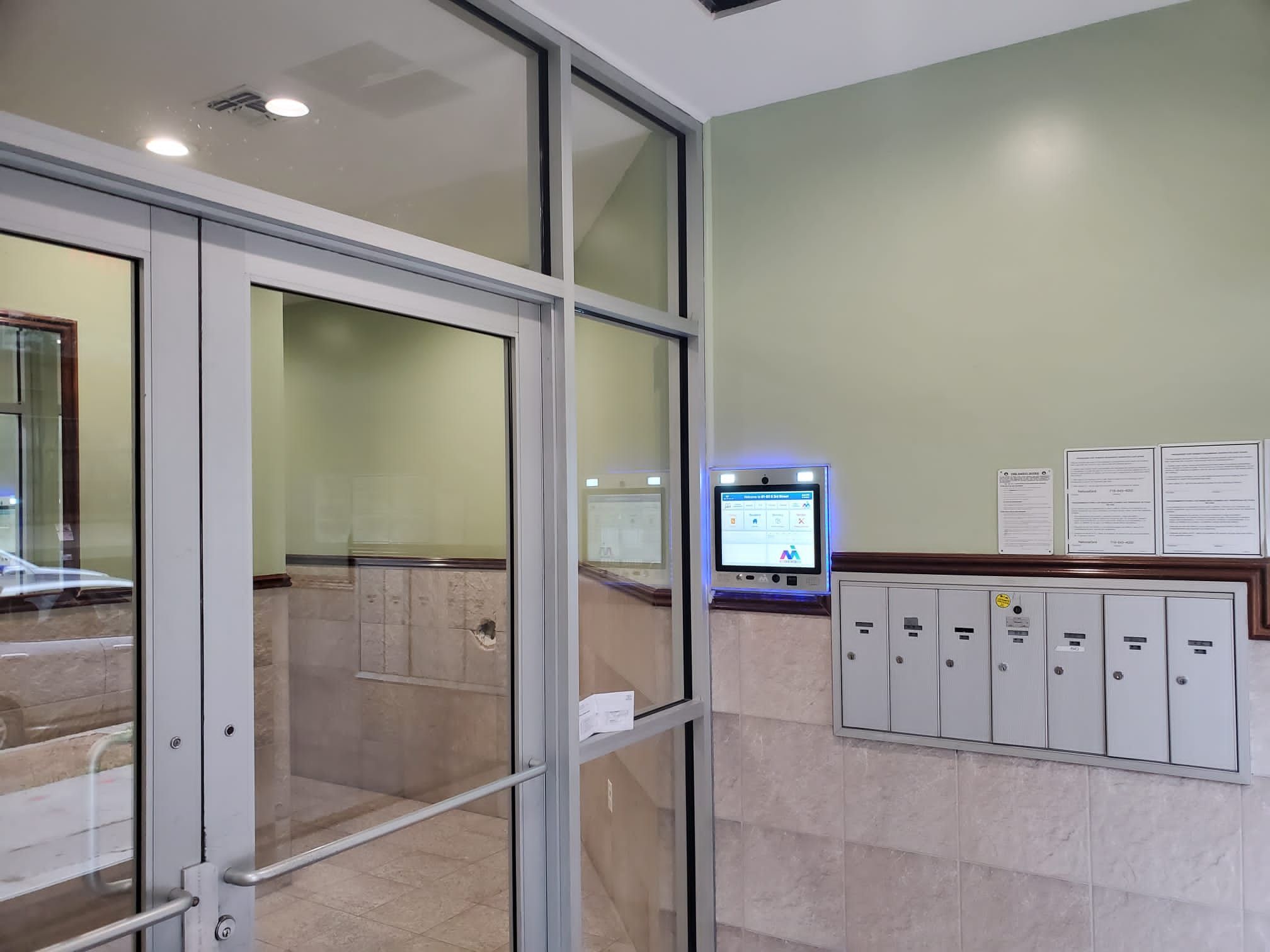 mvi keycom mounted on green and stone wall by building entrance