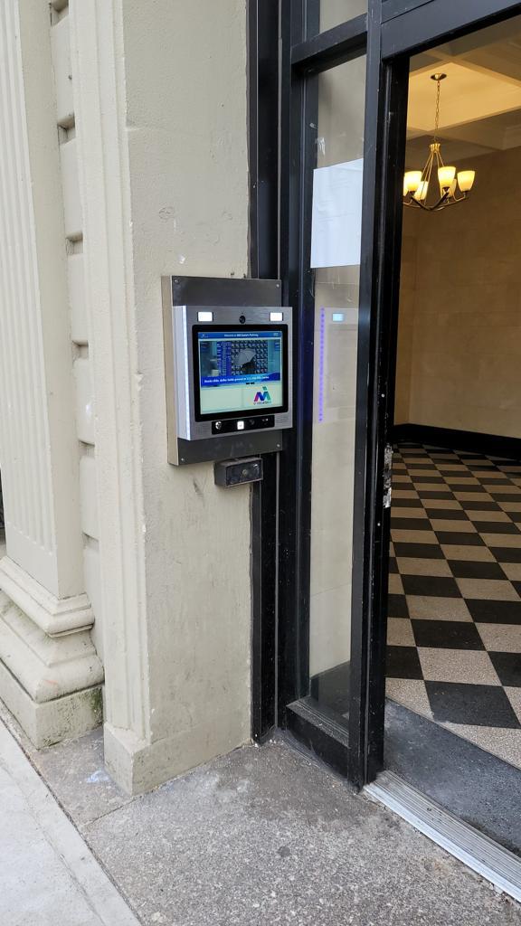 mvi keycom system mounted on white stone wall by building entrance