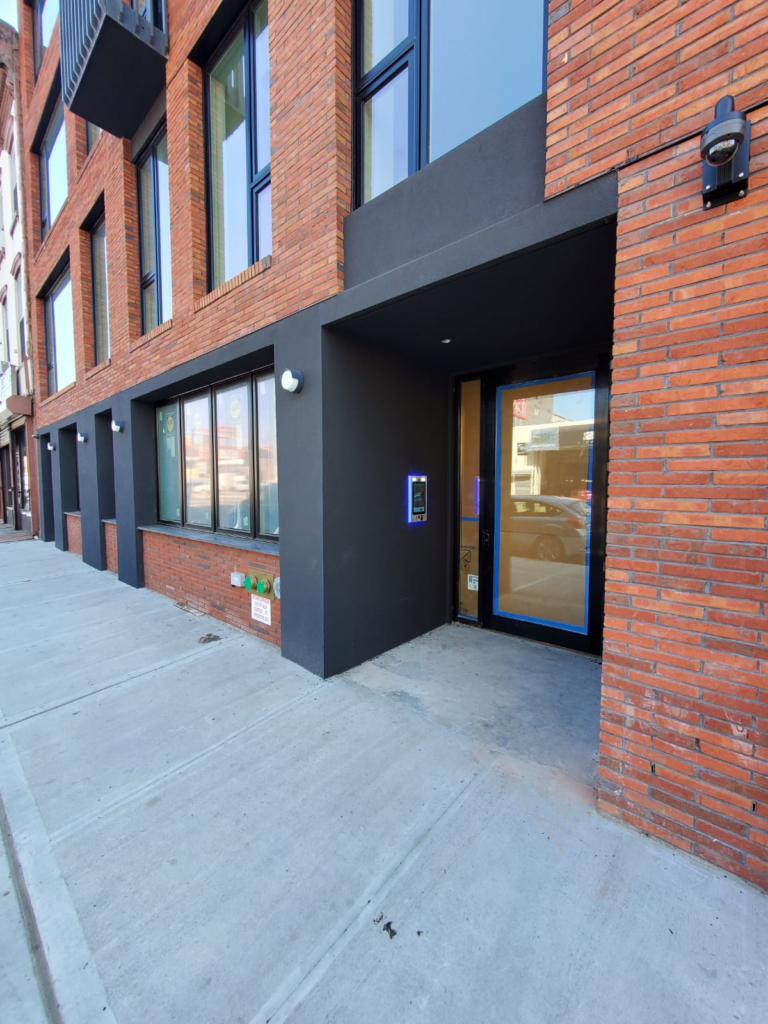 brick building with mvi keycom mounted on black wall by building entrance